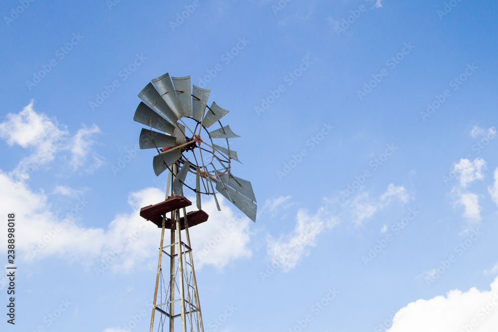 Traditional Windmill. Traditional farm windmill set against sunny blue sky. Horizontal orientation with copy space and natural color. Traditional Windmill. Traditional farm windmill set against sunny blue sky. Horizontal orientation with copy space and natural color.