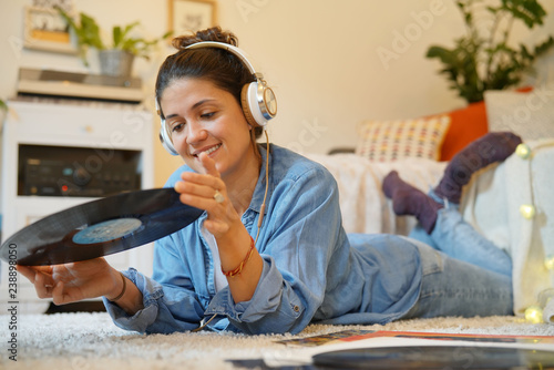 Attractive brunette listening to vinyl records on floor at home