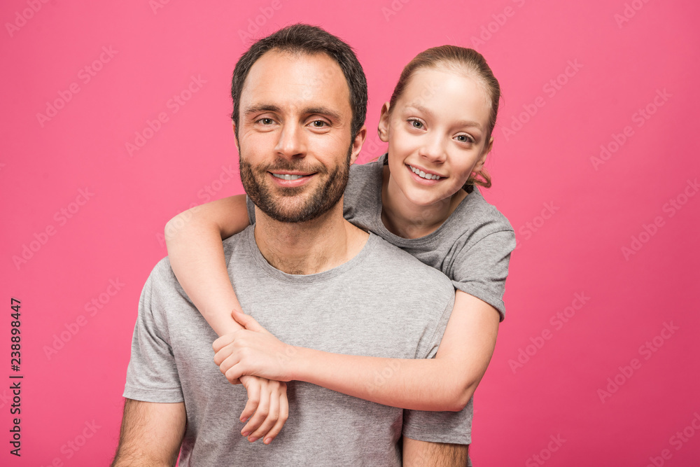 smiling blonde daughter hugging her father, isolated on pink smiling blonde daughter hugging her father, isolated on pink