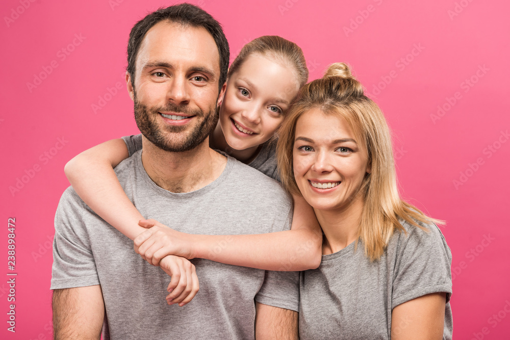 smiling daughter hugging her happy parents, isolated on pink smiling daughter hugging her happy parents, isolated on pink
