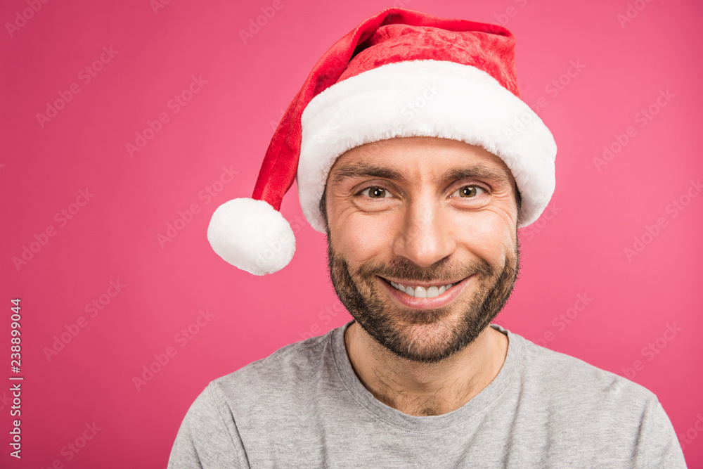 portrait of handsome smiling man in santa hat, isolated on pink portrait of handsome smiling man in santa hat, isolated on pink