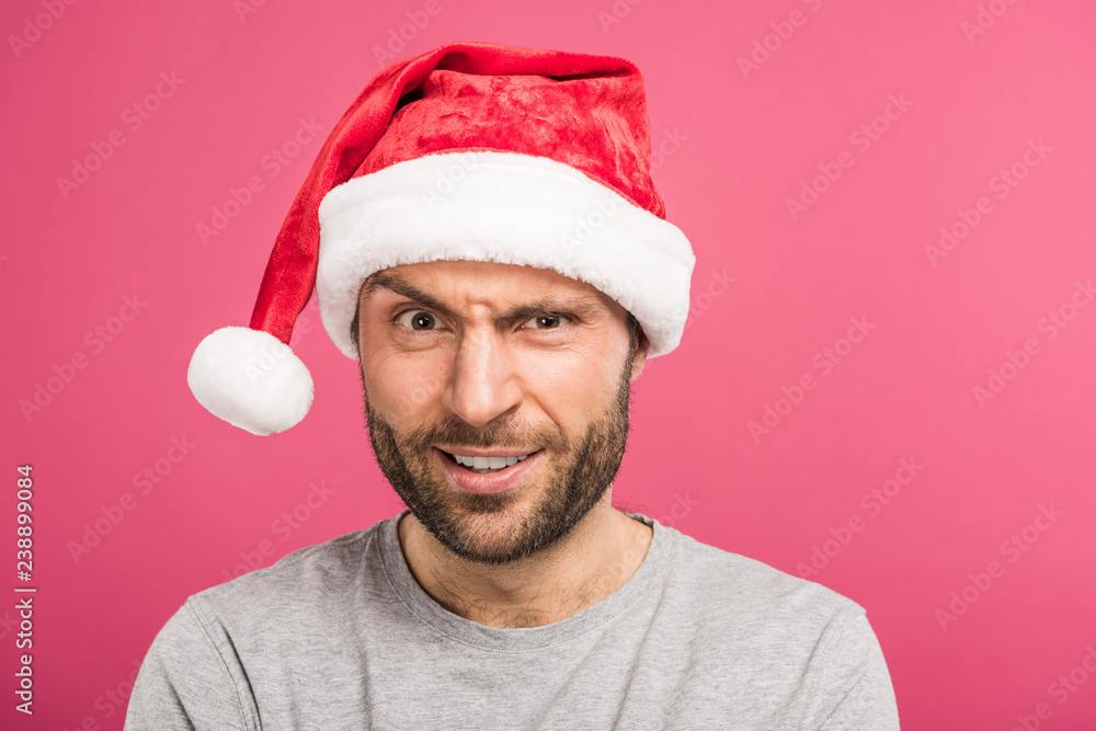portrait of funny confused man in santa hat, isolated on pink portrait of funny confused man in santa hat, isolated on pink