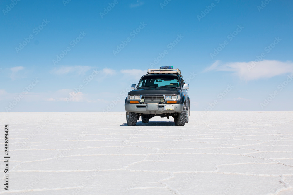 Car on the Uyuni Salar in Bolivia.  Blue Sky and white salt background.