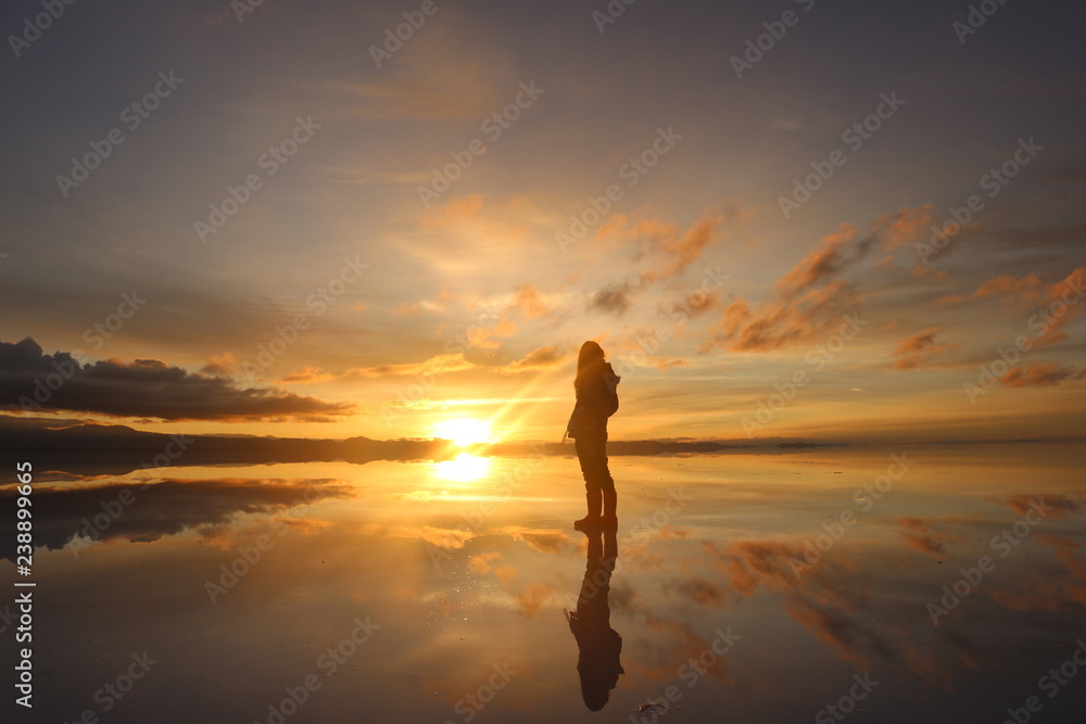 ウユニ塩湖で日の出を見つめる女性
