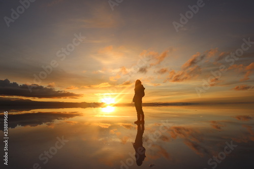 ウユニ塩湖で日の出を見つめる女性