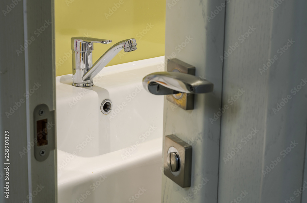 Obraz premium View through the open door to the faucet on the washbasin in the bathroom