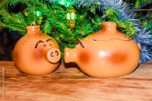 New Year's card yearof the pig piglet doll pots on the background of a dressed Christmas tree photo