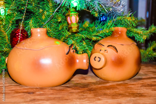 New Year's card yearof the pig piglet doll pots on the background of a dressed Christmas tree photo