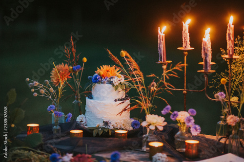 Wedding cake on table with candles outdoors photo