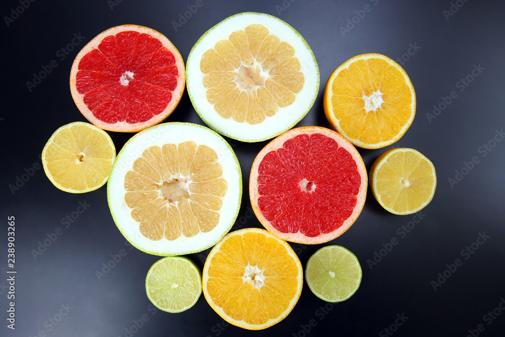 cut pieces of different citrus fruits on dark background cut pieces of different citrus fruits on dark background