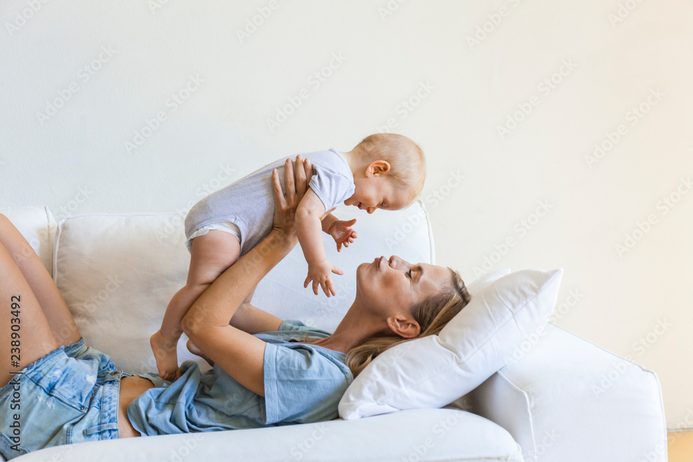 Mother playing with her baby girl on couch Mother playing with her baby girl on couch
