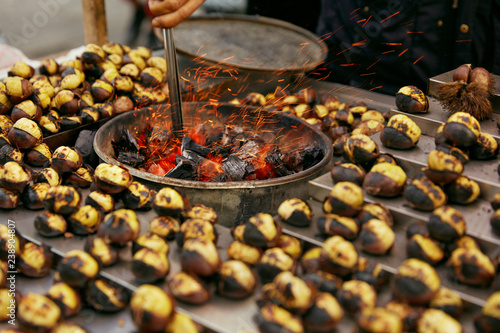 Fototapeta Naklejka Na Ścianę i Meble -  Street Food Market. Cooking Roast Chestnuts On Charcoal Closeup