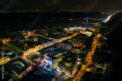 Urban landscape at night. Lights of Podil in Kiev. Colorful bridge on the background