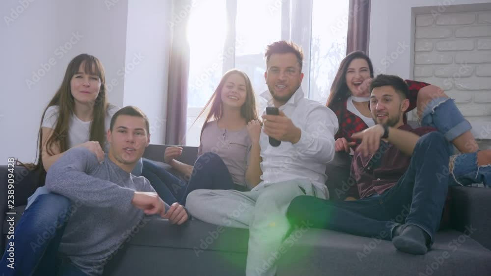 football fans in backlight, running friends jump on the sofa and turn on the TV to watch the match and then celebrating success with high five and excited gestures football fans in backlight, running friends jump on the sofa and turn on the TV to watch the match and then celebrating success with high five and excited gestures