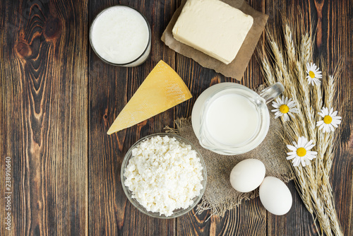 Dairy products with ears and chamomile on wooden background.