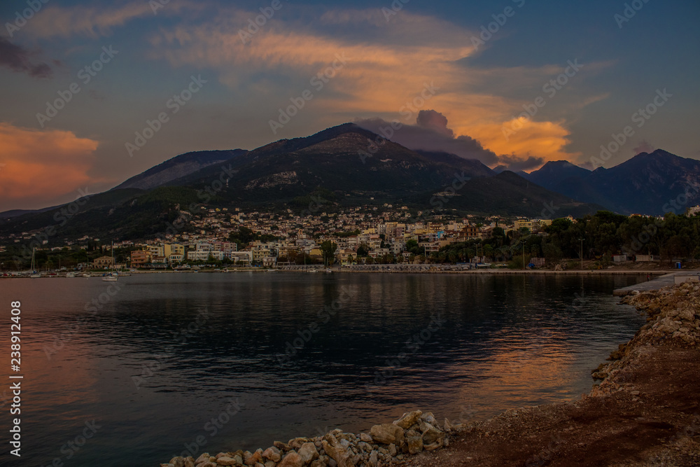 lonely mountain and small south city under it in sea bay cozy harbor in twilight evening darkness after sunset 