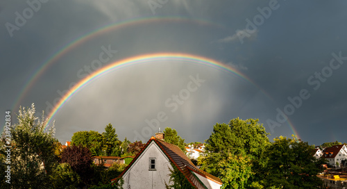 full double rainbow over dramatically lit houses