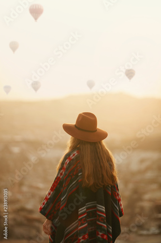 Travel. Woman In Hat With Flying Balloons In Sky At Sunset