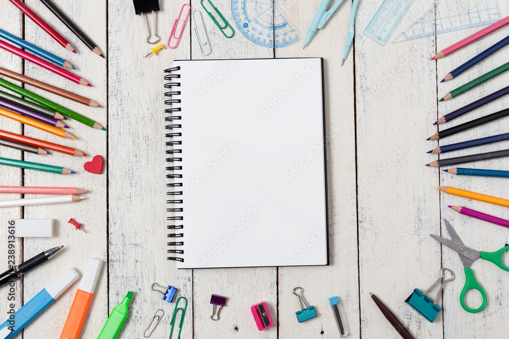 Empty notebook and colorful pencils on white wooden table