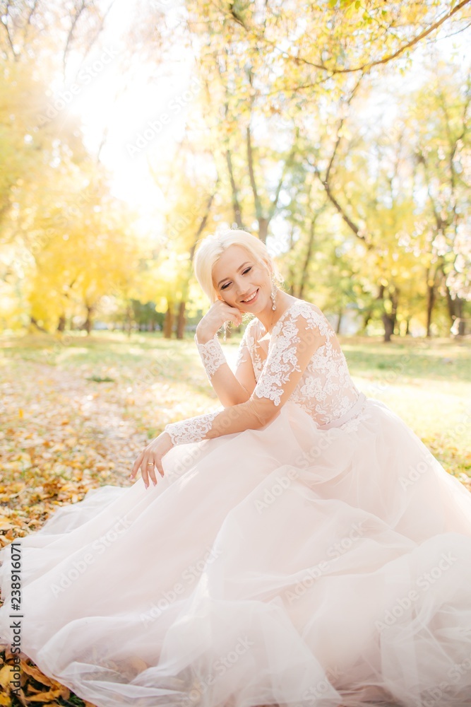 Beautiful blonde bride in white dress in the garden