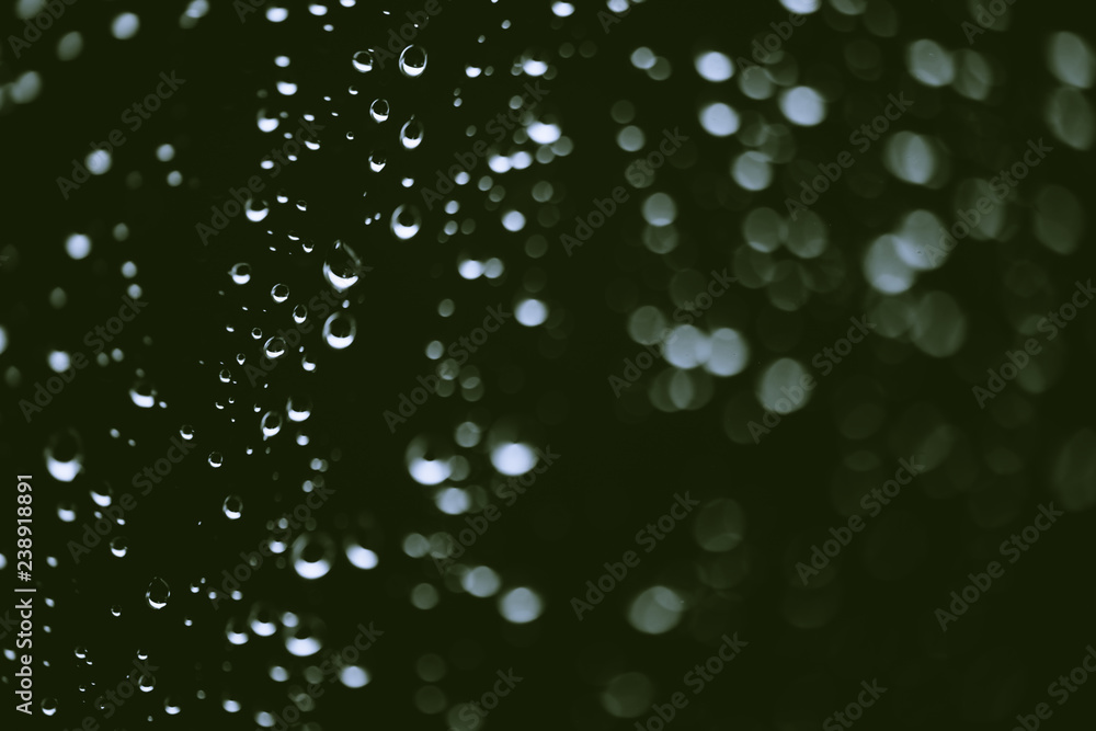 Dirty window glass with drops of rain. Atmospheric green background with raindrops in bokeh. Droplets and stains close up. Detailed transparent texture in macro with copy space. Rainy weather. Dirty window glass with drops of rain. Atmospheric green background with raindrops in bokeh. Droplets and stains close up. Detailed transparent texture in macro with copy space. Rainy weather.