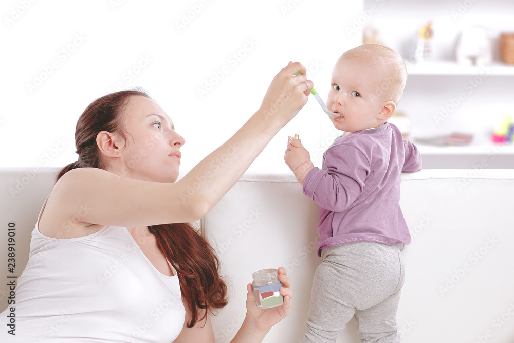 young mother feeds the baby fruit puree. young mother feeds the baby fruit puree.