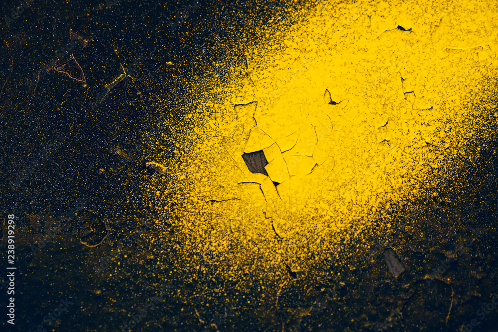 Rough dark black wall with yellow sprays of dye. Colorful background