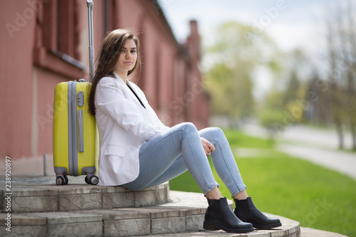 Beautiful fashionable happy girl, hipster, in the terminal at the airport with suitcase.