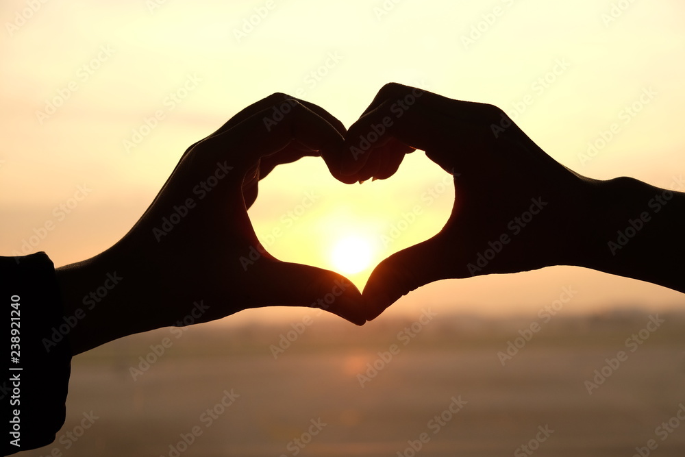 Fototapeta premium Heart shape from two hand with sunrise background.