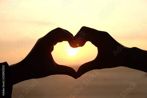 Heart shape from two hand with sunrise background.