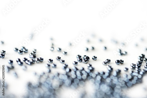 Fotografie Shining black seed beads scattered on textile background close up