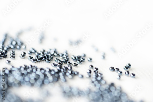 Shining black seed beads scattered on textile background close up