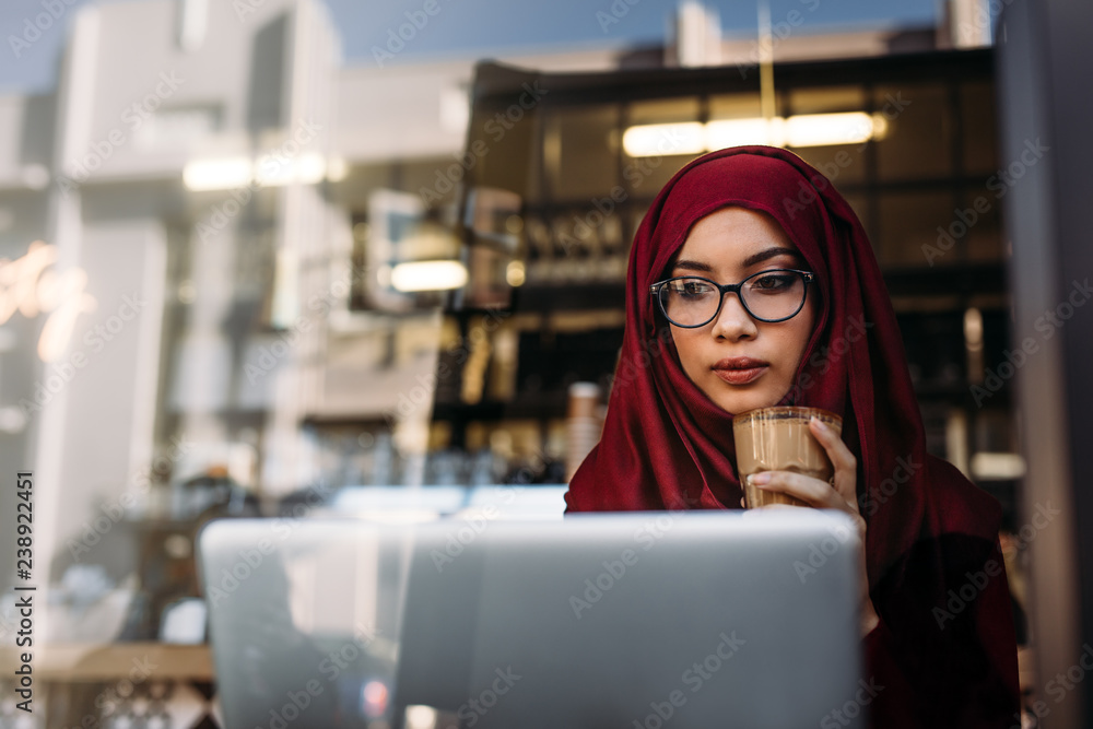 Hijab girl with coffee using laptop at cafe