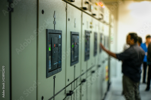 Blurred portrait of technician doing the preventive maintenance in the control room. Workers monitoring the status of electronic devices by check list.