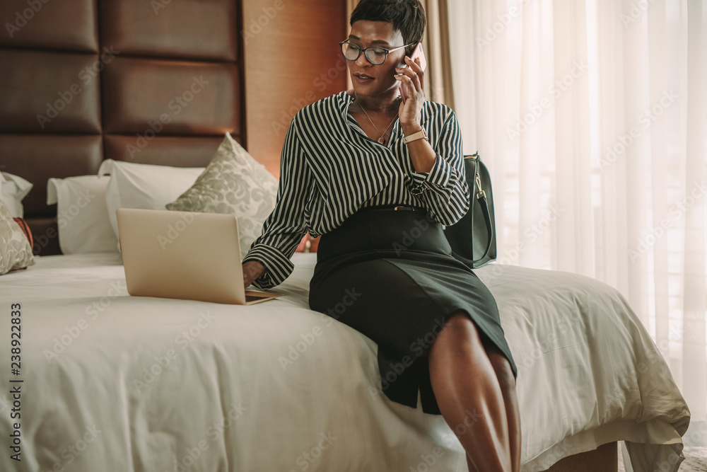 Obraz premium Business woman in hotel room using laptop and smartphone
