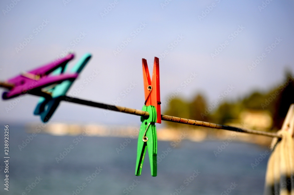 closeup of colourful clothespins hung on a laundry line rope on a blue seaside background closeup of colourful clothespins hung on a laundry line rope on a blue seaside background