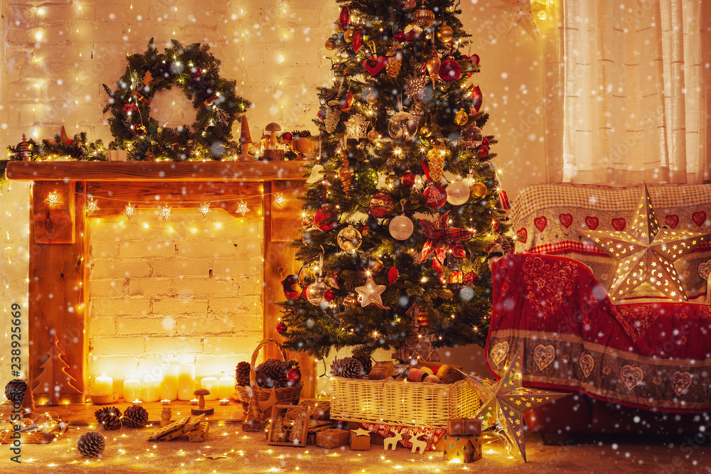 Christmas living room interior, decorated wood mantelpiece, lit tree with red gold green baubles, stars, wreath, candles, lightly toned, cosy chair with red cover, created snow, selective focus