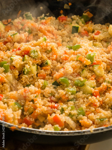 Mixing quinua with onion, red and green pepper and courgette in a frying pan. Cooking quinua with vegetables, recipe of quinua and vegetables