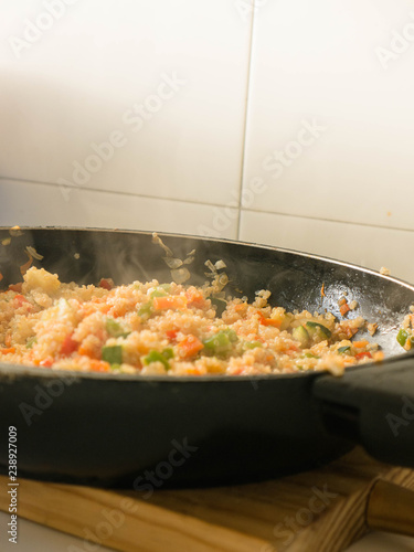 Mixing quinua with onion, red and green pepper and courgette in a frying pan. Cooking quinua with vegetables, recipe of quinua and vegetables