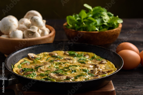 Omelette with mushrooms and cheese, on dark wooden background.