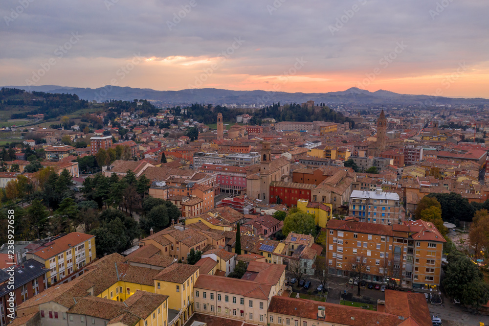 Fototapeta premium Sunset aerial panorama of Cesena in Emilia Romagna Italy near Forli and Rimini, with the medieval Malatestiana castle, Piazza del Popolo and Roman Catholic churches and cathedral on a winter afternoon