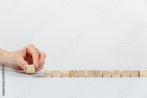 Closeup of businessman making a pyramid with empty wooden cubes.