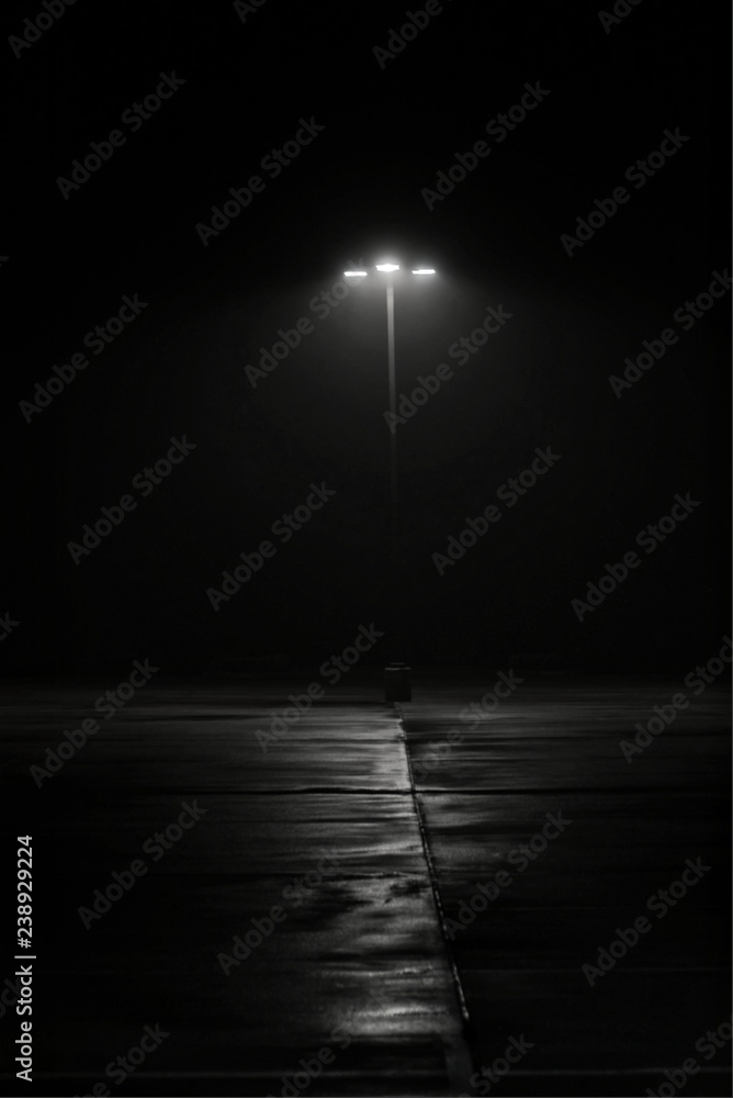 Φωτογραφία Street lamp on dark night, deserted film noir black and white mystery shadows eerie minimalist copy space vertical format