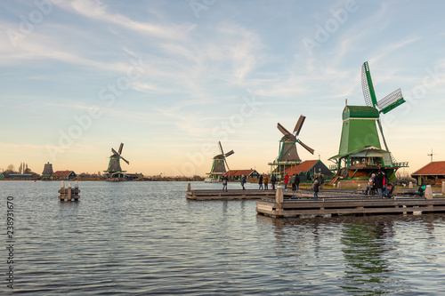 Picturesque typical autumn Dutch windmill landscape with a row of a diverse type of windmills on a river shore during the day with an intense blue sky