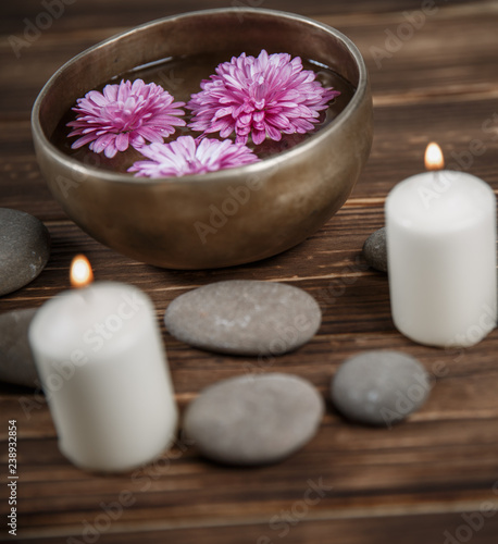 Singing bowl with candles with pebbles on dark wooden background