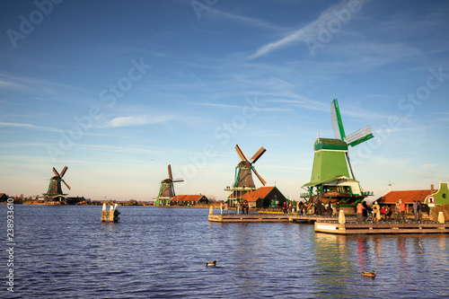 Picturesque typical autumn Dutch windmill landscape with a row of a diverse type of windmills on a river shore during the day with an intense blue sky