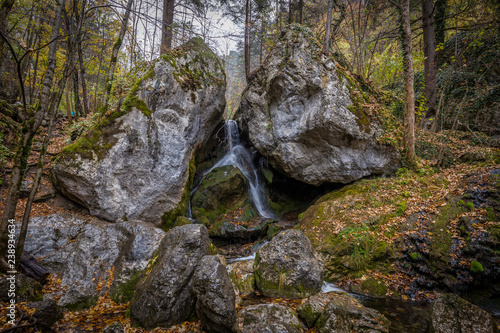 Water falling between two large rocks in autumn forest at Myrafälle, Austria photo