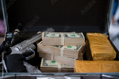 Drug trafficker holding a lot of cash on hand and use gun pushing drugs to the customer in the Drug dealing, concept about the drug problem