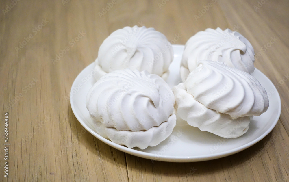 four zephyr (marshmallows) on a wooden table four zephyr (marshmallows) on a wooden table