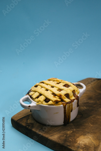 sweet apple pie on wooden board on blue background with copy space